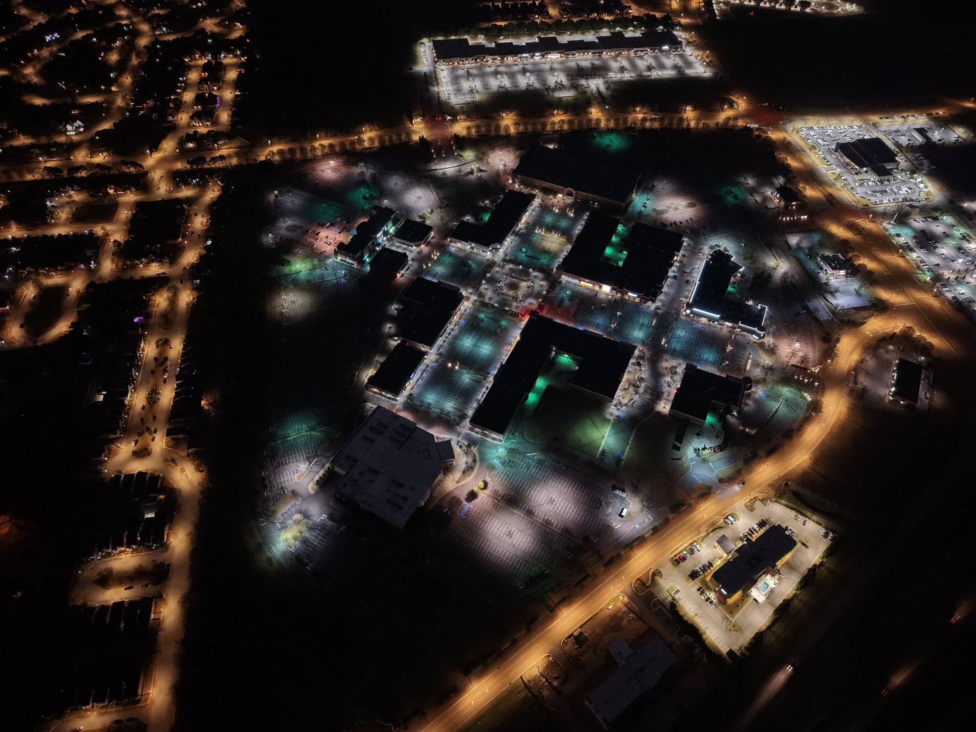 Aerial view of shopping center at night before LED retrofit - mixed color temperatures and uneven light coverage