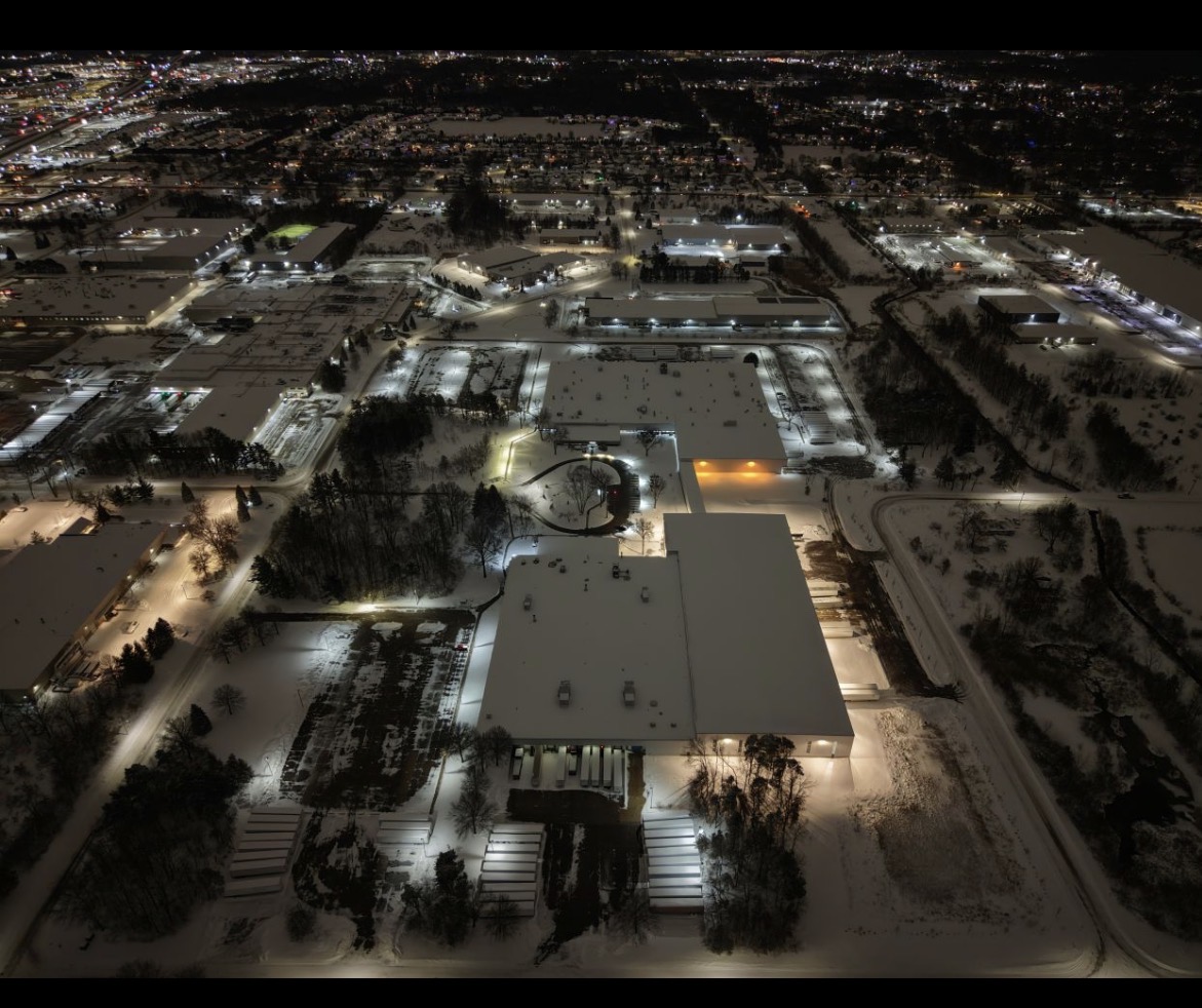 Shopping center parking lot at night before LED retrofit - legacy HID fixtures burning full power