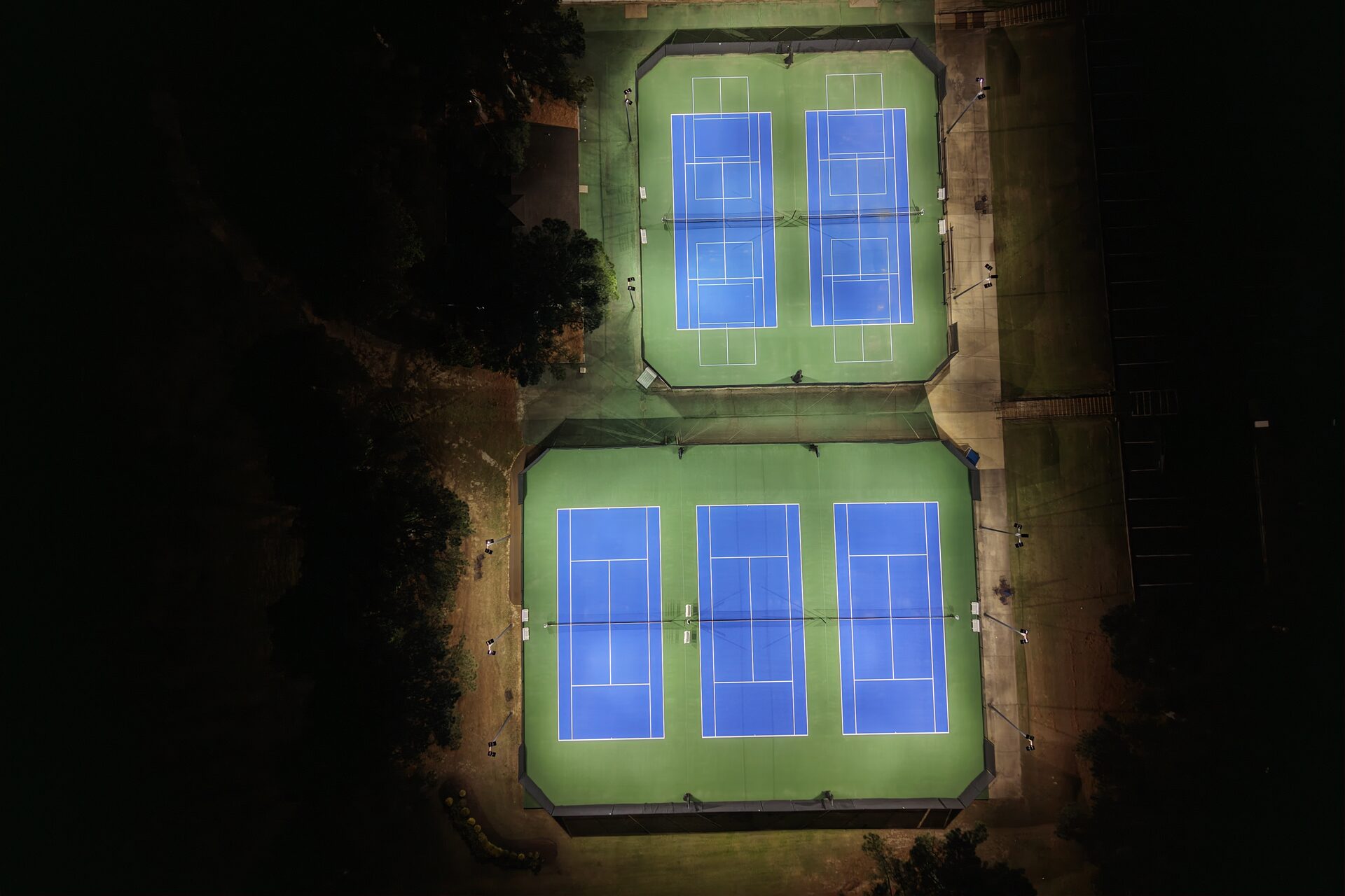 Top-down aerial view of tennis courts at Windyke Country Club illuminated by eneroi LED lighting, showing perfectly uniform light distribution with zero shadows or hotspots
